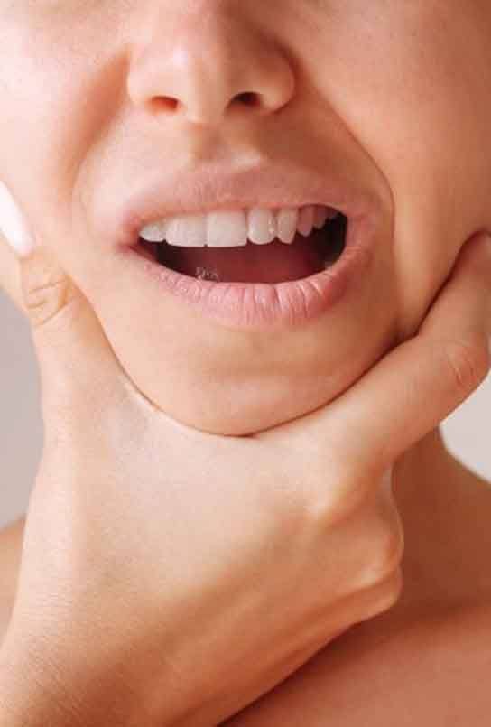 Woman holding her jaw as she experiences TMD pain