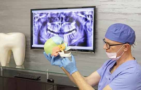 Dentist using model to explain TMJ treatment options