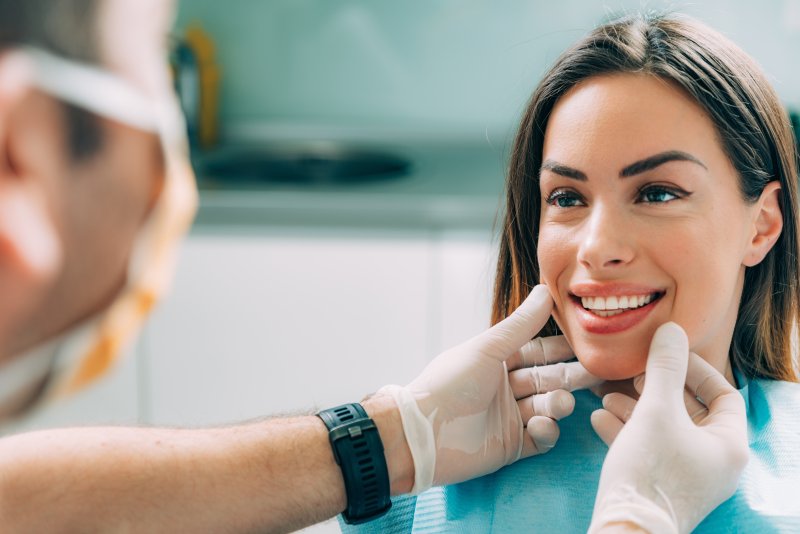 A dentist examining a young woman’s smile