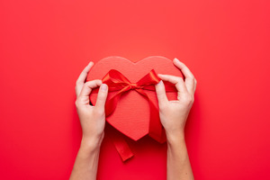 Tying a ribbon on a heart-shaped box of chocolates